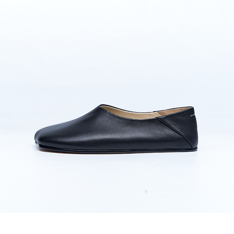 Black leather flat with structured upper and refined opening, designed for modern women’s flat shoe development