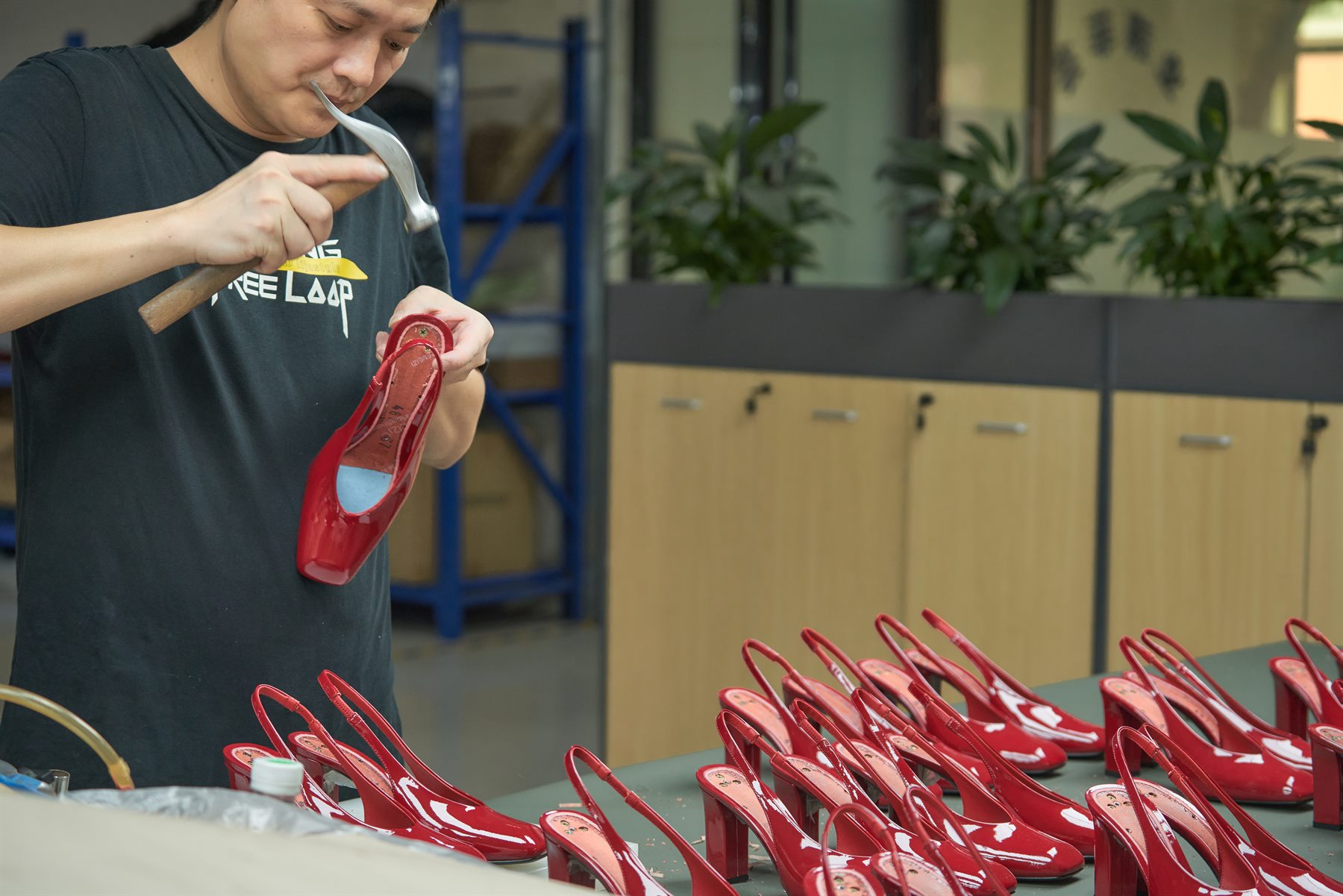 Kaimoo craftsman checking red women’s shoes during small batch footwear production
